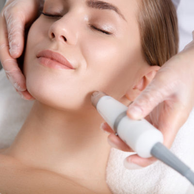 Calm young woman getting cavitation rejuvenation skin treatment