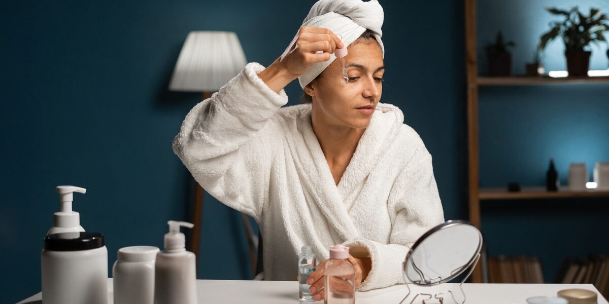 Beauty procedure at home. Hispanic woman holding pipette with anti wrinkle serum near eye, looking at mirror, sitting at her bedroom in the evening Woman applying anti-wrinkle serum near eye during home beauty routine