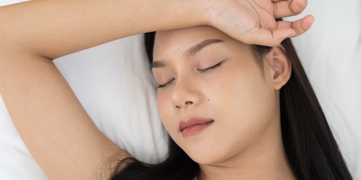 Young Asian woman sleeping on bed and keeping eyes closed